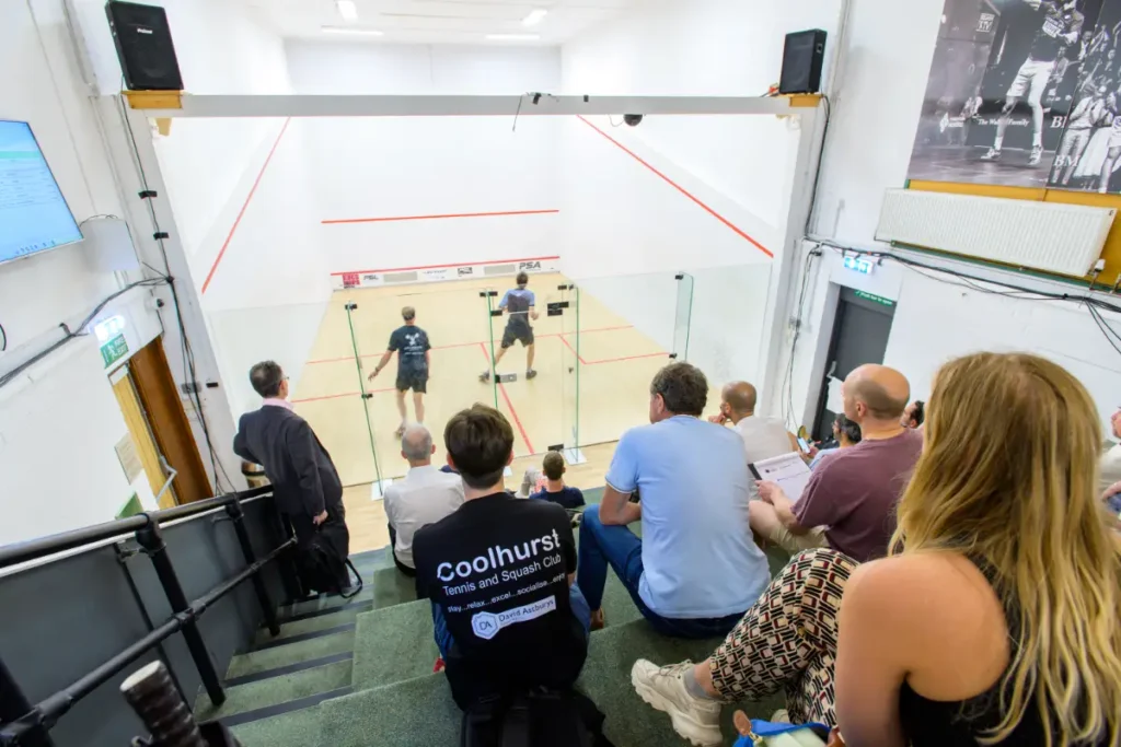 Coolhurst Club squash gallery filled with spectators watching a live match.