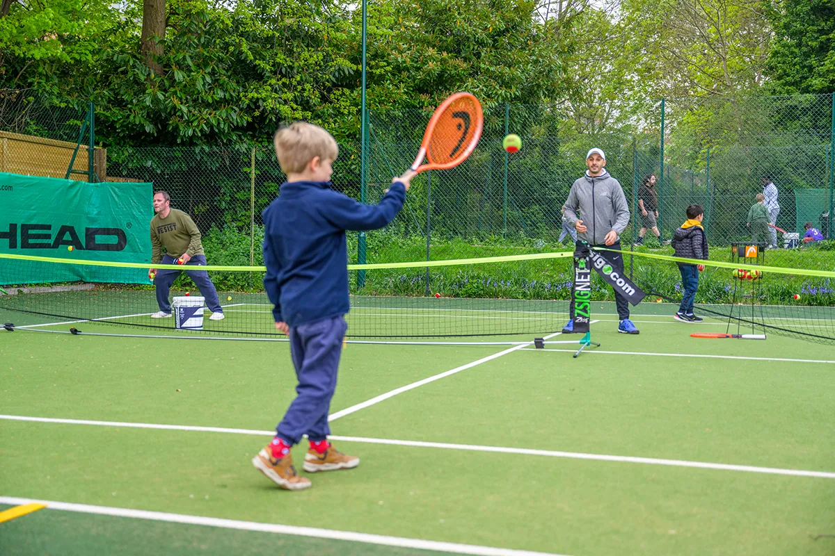 Child practicing tennis with coach during Coolhurst holiday camp.